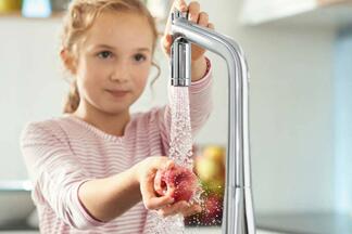Kind wäscht Obst unter Wasserhahn