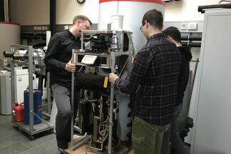 Drei Männer positionieren ein Solvis-Technik-Modul.