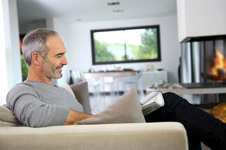 Mann im Wohnzimmer mit Kamin liest eine Zeitung