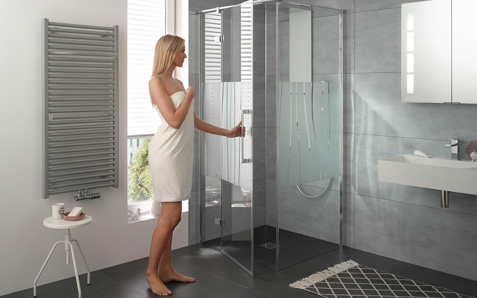 Frau in Handtuch öffnet die Duschtür der AtelierPlan Duschkabine von HSK 